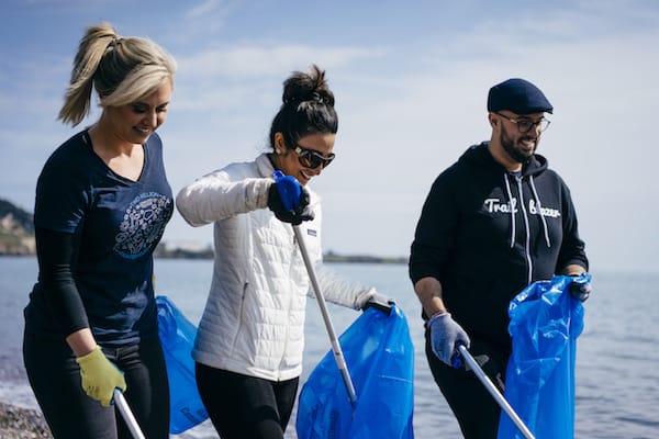 Three employees clean up a beach