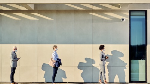 Socially distanced customers queue outside a government building