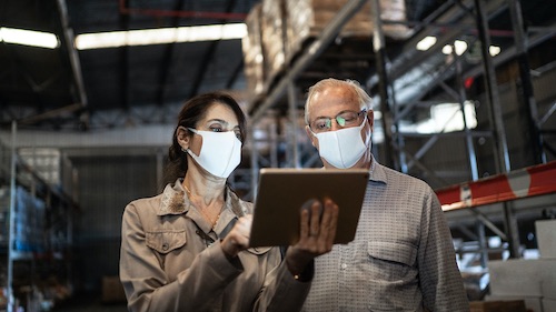 Colleagues wearing face masks at work in a manufacturing facility