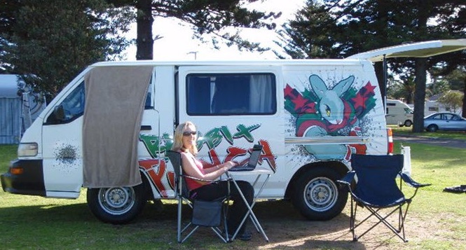 Heather Black works on her laptop in front of a van in Australia