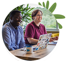 Two smiling people sitting in a Salesforce Tower with their laptops