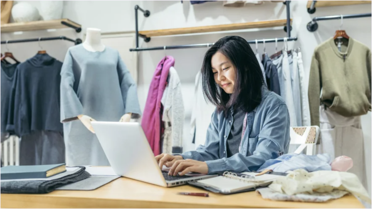 Retail employee in a store working on laptop.