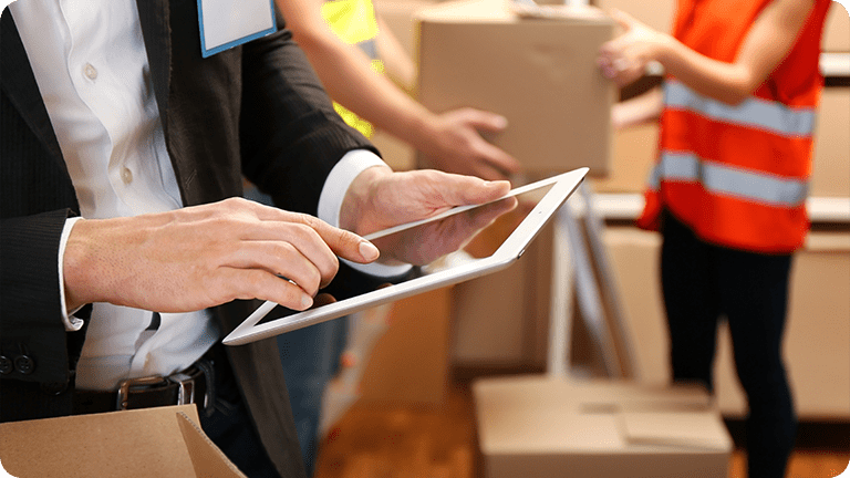 A man on a tablet with shipping boxes around