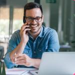 Sales rep smiling and talking on the phone while using a laptop and sales prospecting tools.