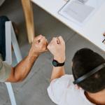 Excited call centre agents, fist bump and celebrating deal, promotion and sale from above in office.