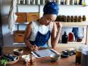 person working at a desk with a tablet computer surrounded by jars and shelves of herbs and tinctures