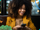 Woman in a jacket checking her phone and smiling / email deliverability