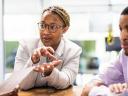 Businesswoman, professionally dressed, sitting at a table and leading a meeting in an office / marketing quotes