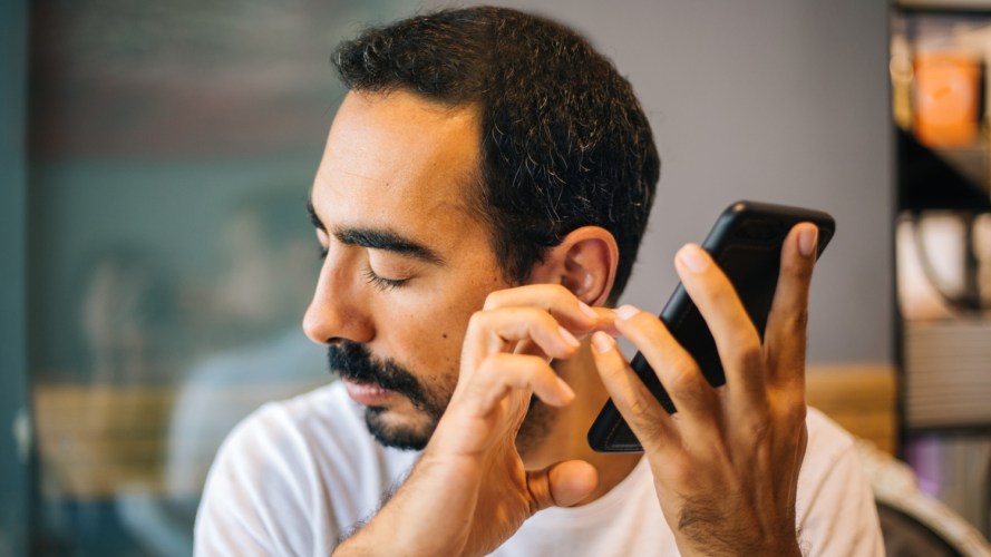 A blind man uses assistive technology on his phone to access content.