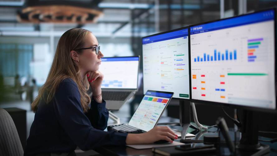 Professional reviewing B2B sales automation and RevOps analytics dashboards on multiple screens.