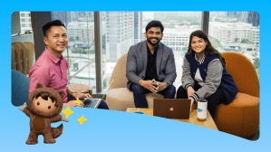 Salesforce employees collaborate around a laptop.