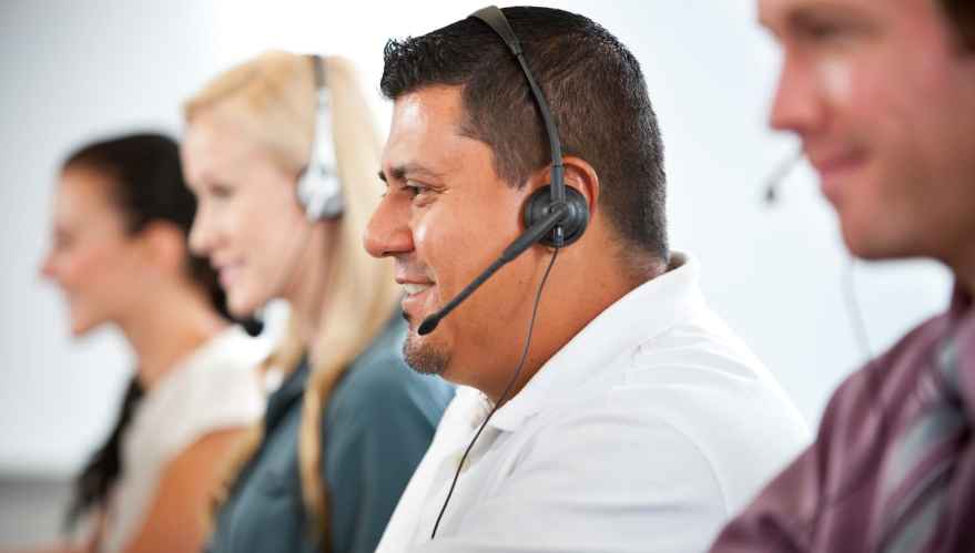 Four people wearing operator headsets in a customer service center