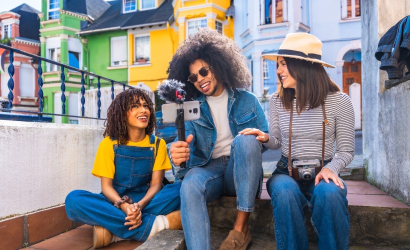 Smiling friends taking videos on a colorful business front steps