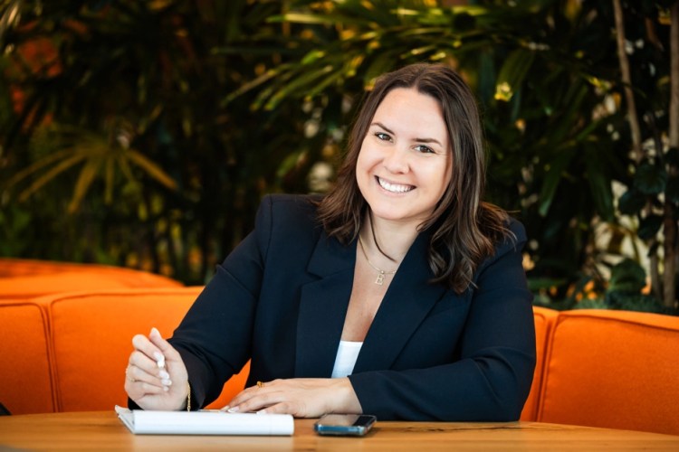 A woman sitting at a desktop, smiling at the camera.