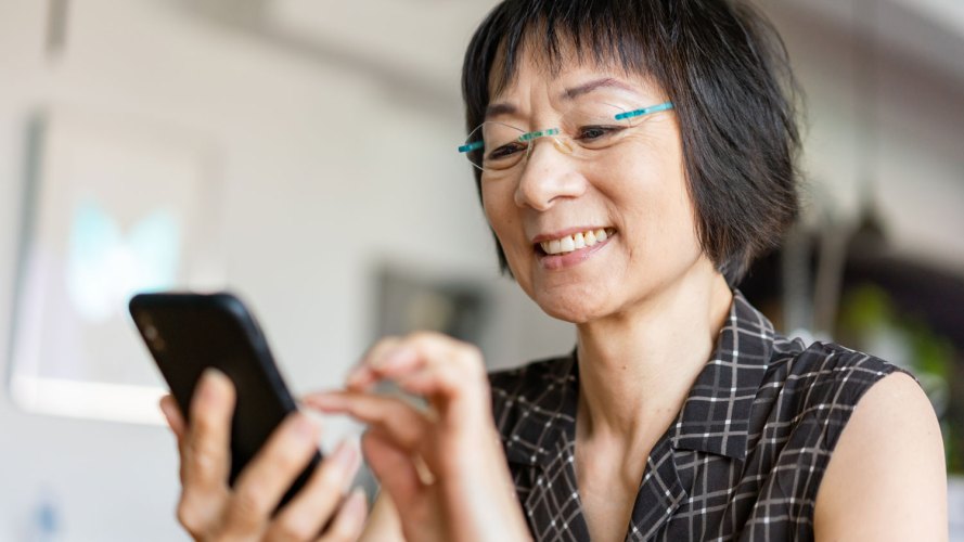 what is a chatbot? woman wearing glasses holding and interacting with her smartphone