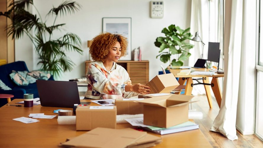 person sitting at their desk covered in small shipping boxes