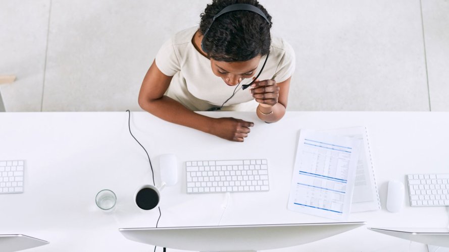 a person on a phone headset sitting at a laptop