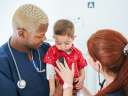 Two healthcare professionals give a baby a checkup
