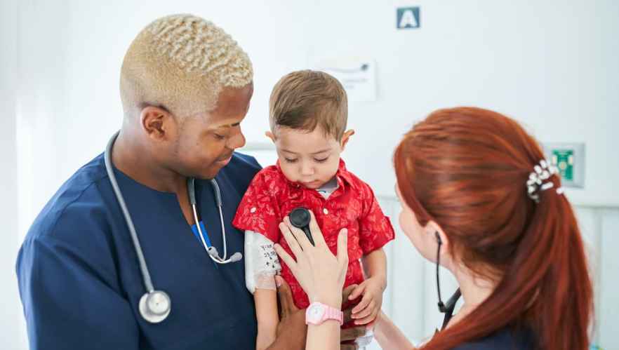 Two healthcare professionals give a baby a checkup
