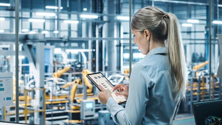 Woman in a factory, holding a tablet while reviewing field service metrics