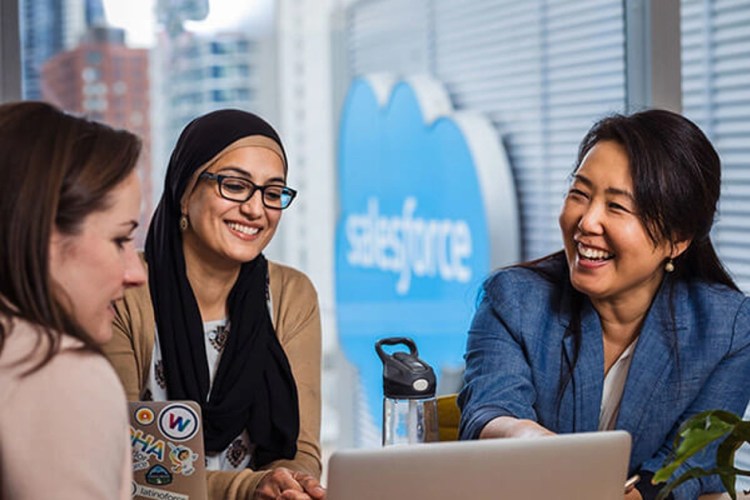 Three Salesforce employees are talking in an office.
