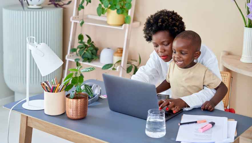 Woman and her child working on her laptop in her home office