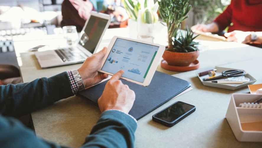 People around a conference table with laptops and tablets using sales forecasting techniques