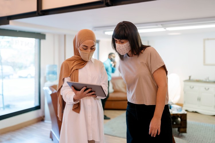 Coworkers Wearing Face Masks Using Tablet