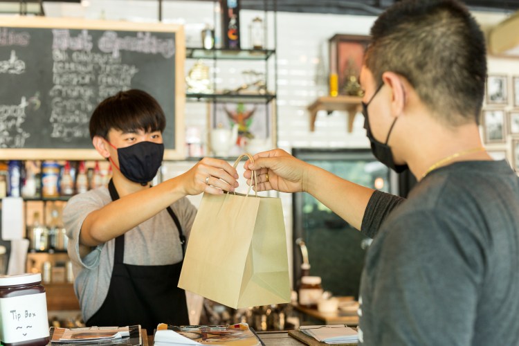 Person picking up food at a local cafe while wearing a mask