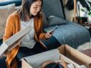 A woman looks at a phone while opening a shoebox: consumer goods data.