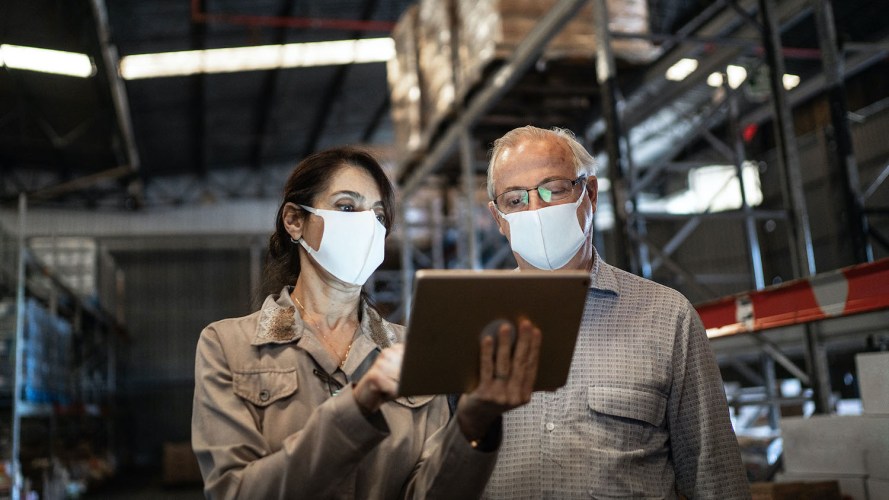 Face-mask wearing colleagues in a warehouse