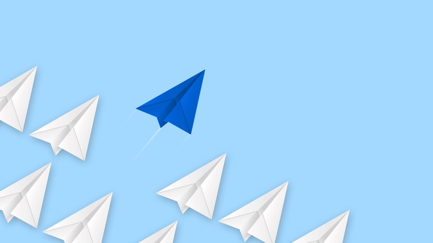 illustration of one blue paper airplane flying high above many white paper airplanes