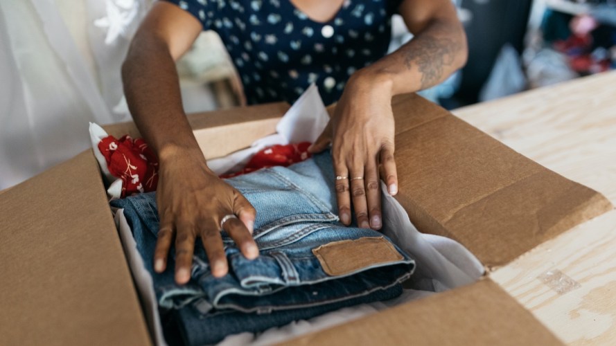 Woman packs jeans in a box