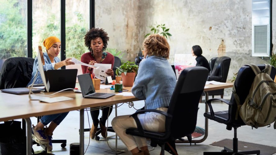 Multi ethnic women at a workplace conference table: Equal Pay Day