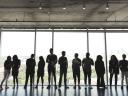 Eleven people standing in front of large backlit glass windows