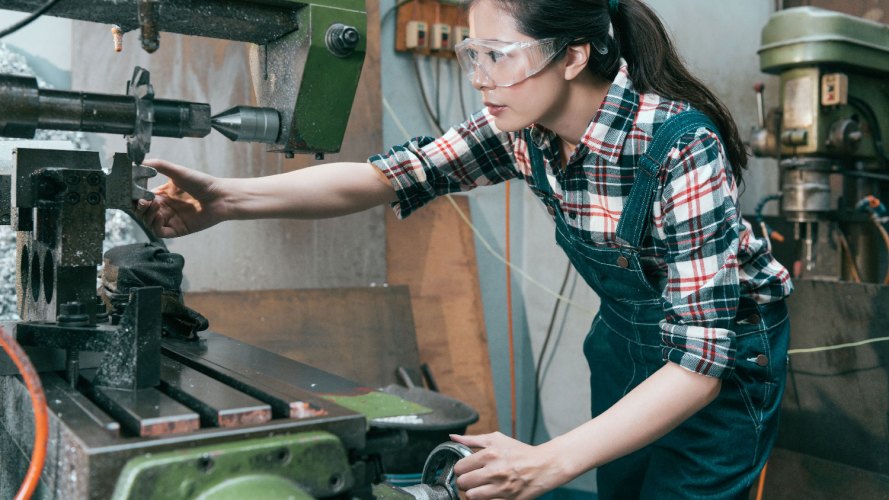 side view woman working on industrial manufacturing equipment / manufacturing partners