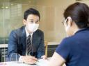 man and woman on opposite site of glass screen wearing masks public sector