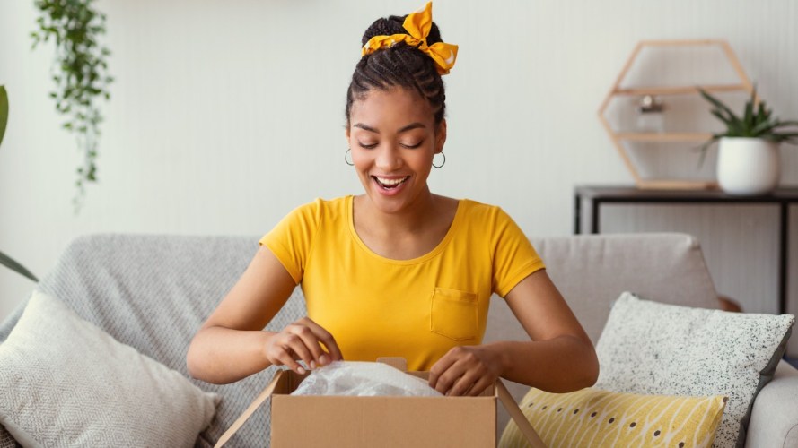 A woman opens a delivery box, the impact of ecommerce on retail industry.