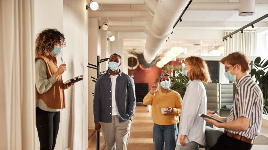 Masked office workers talking