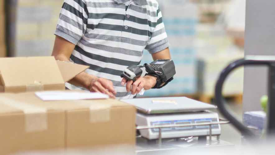 Worker wears a high-tech IoT wristband while packing and shippping