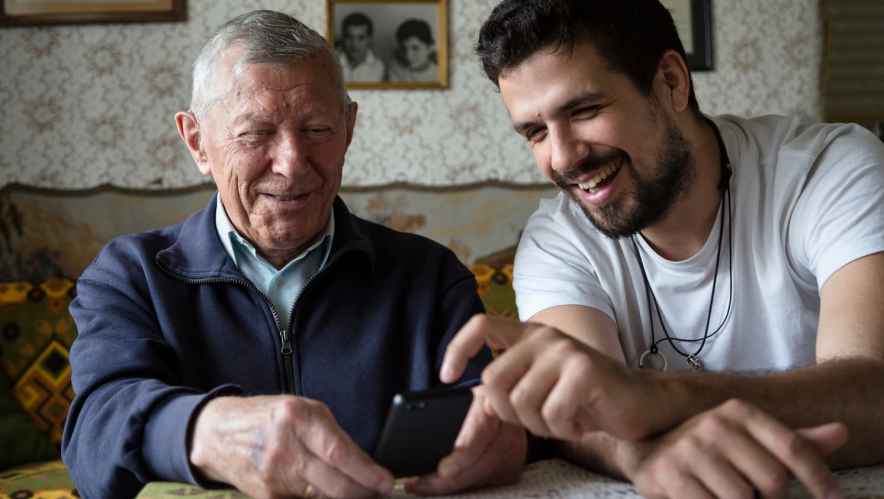 Older man and younger man using a cell phone together