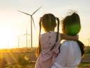 backs of woman and child as they look at wind turbines energy economy utilities, E&U