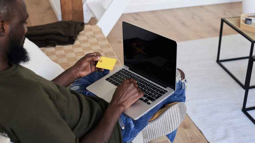Man holding a credit card using his laptop