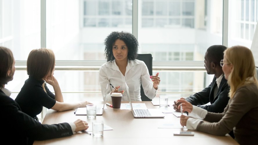 Black woman at the head of a conference table, surrounded by work colleagues what is sales management