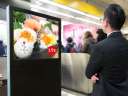 man looking at an AI smart digital advertising billboard that is suggesting sushi to him