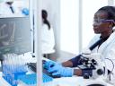 woman scientist in clinical setting in front of a computer in a lab working with decentralized clinical trials information