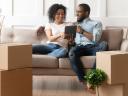 female and male couple sitting on a sofa looking at a tablet while surrounded by moving boxes mortgage lending solutions