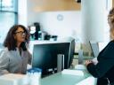 Woman behind a desk talks with another woman in an office setting / increase trust in government services