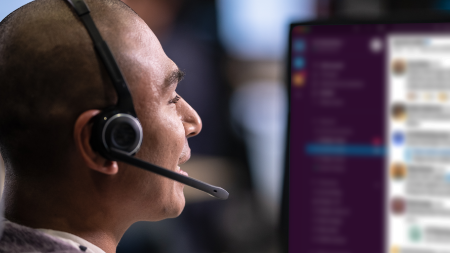 A customer service agent speaks on a headset while his team is case swarming with Slack.