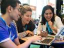 3 colleagues gathered around a laptop for a collaborative Trailhead trail gamification